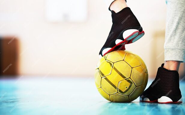 pied-humain-repose-football-sol-beton-photo-ballon-football-baskets-dans-plancher-bois_494741-3039.jpg